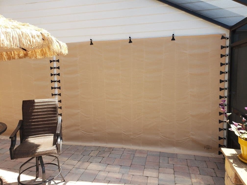 Covered patio with retractable tan shade panels hung from ceiling, wicker chair, and thatched roof element visible on left side