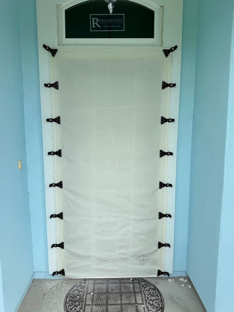 White door with Renaissance business sign and black hardware clips, covered with protective plastic film, set in light blue doorway